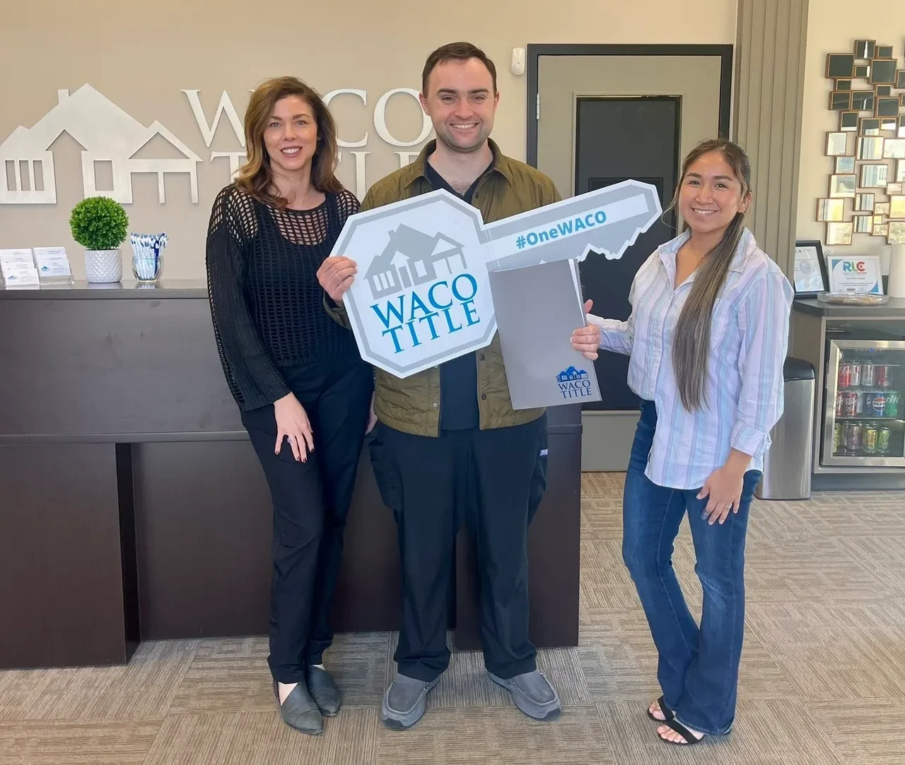 Three people standing in front of a reception desk.