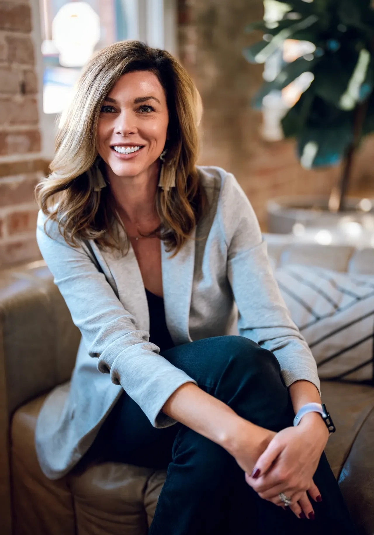 A woman sitting on top of a couch in front of a brick wall.